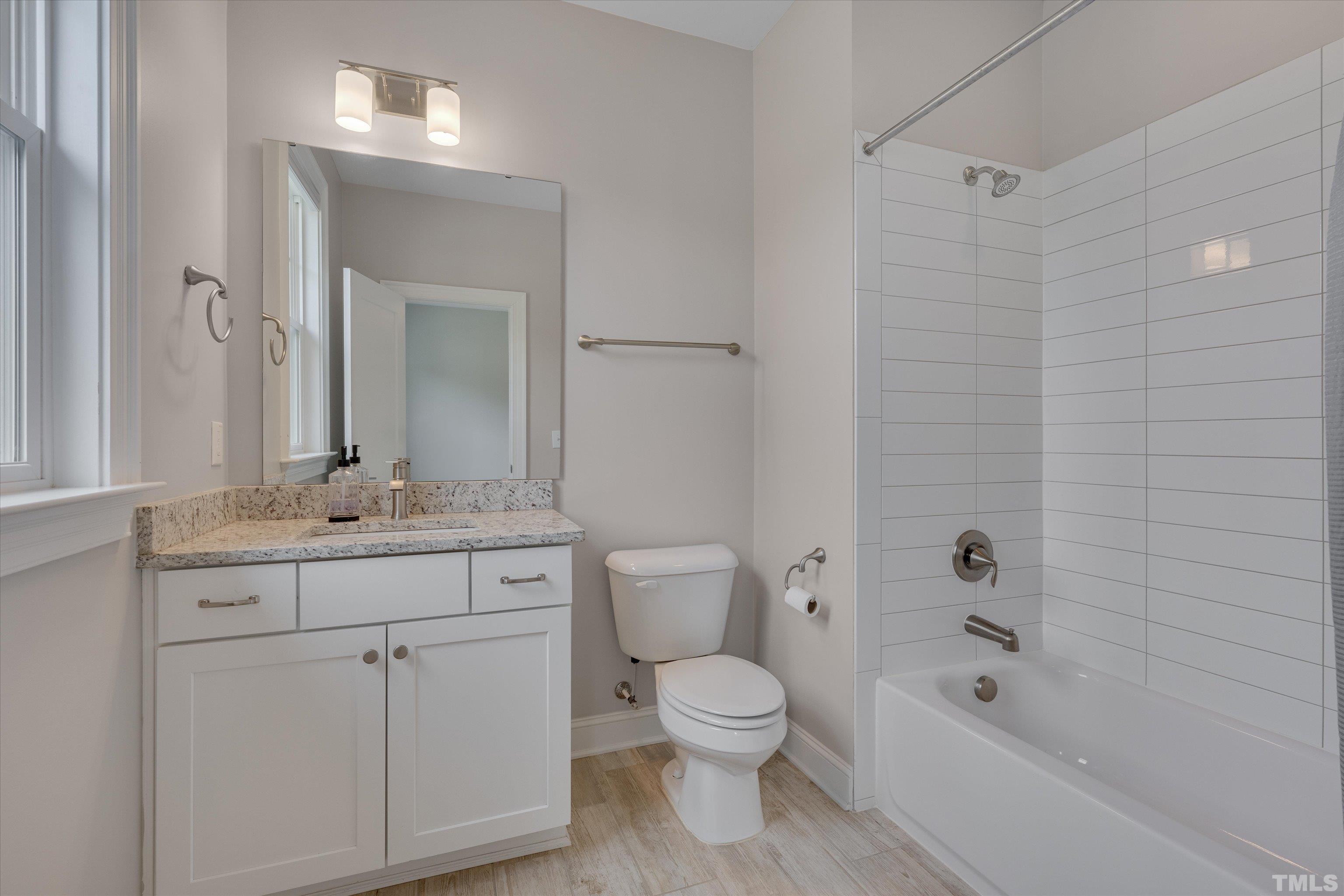 8012 Shree Court Raleigh, NC 27613 - Photo 34 of 49 a bathroom with a granite countertop toilet a sink and a bathtub