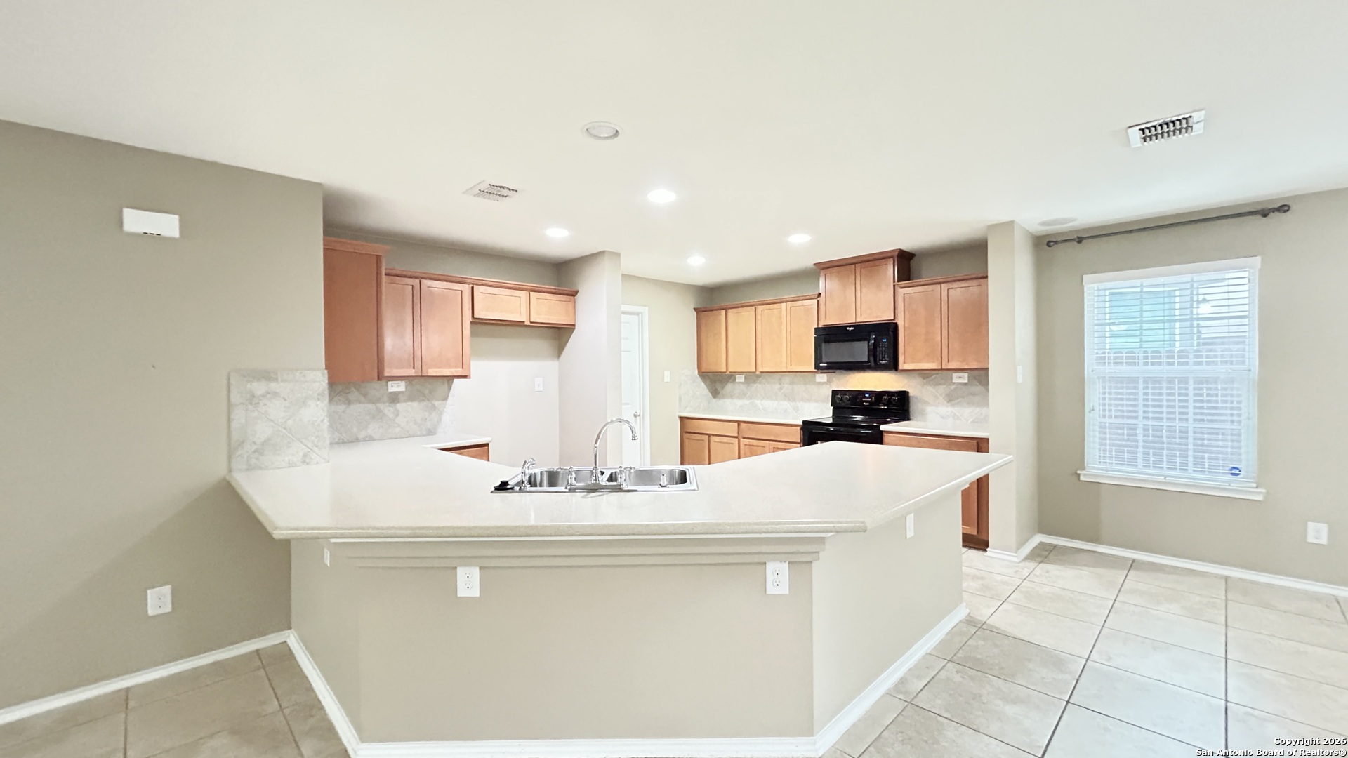 10319 Roadrunner Ridge San Antonio, TX 78245 - Photo 19 of 35 a room with kitchen island stainless steel appliances a sink and a refrigerator