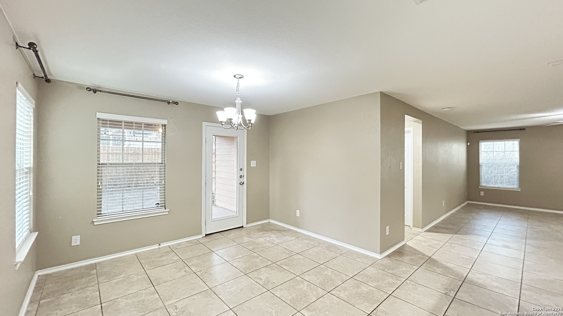 10319 Roadrunner Ridge San Antonio, TX 78245 - Photo 22 of 35 an empty room with chandelier fan and windows