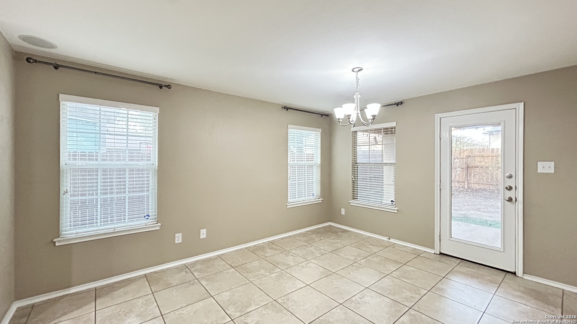 10319 Roadrunner Ridge San Antonio, TX 78245 - Photo 24 of 35 an empty room with chandelier fan and windows