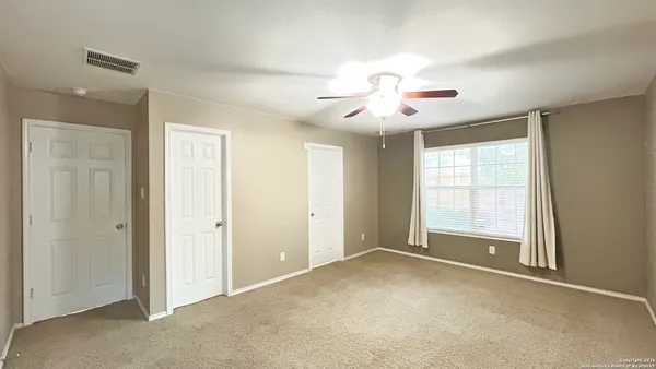 a view of an empty room with chandelier fan and fire place