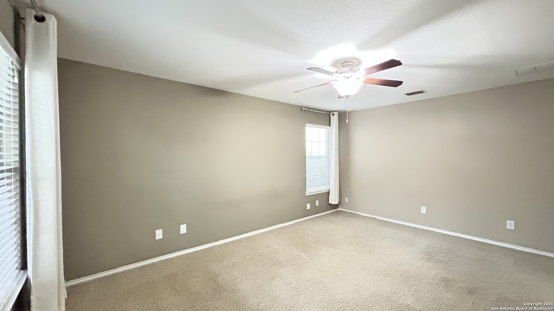 10319 Roadrunner Ridge San Antonio, TX 78245 - Photo 30 of 35 an empty room with a chandelier fan and windows