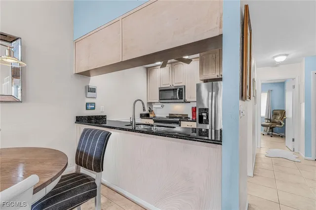 a kitchen with stainless steel appliances granite countertop a refrigerator a sink dishwasher a stove and white cabinets with wooden floor