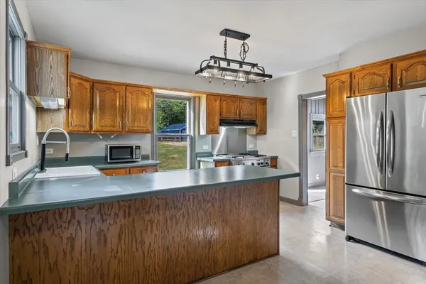 a kitchen with stainless steel appliances a sink a stove a refrigerator cabinets and a dining table