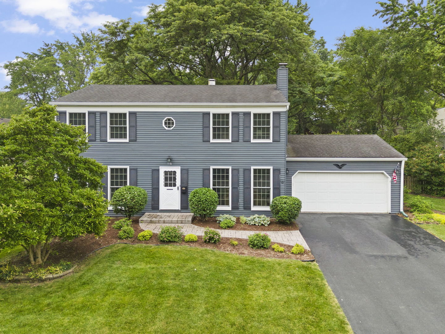 a front view of a house with yard and green space