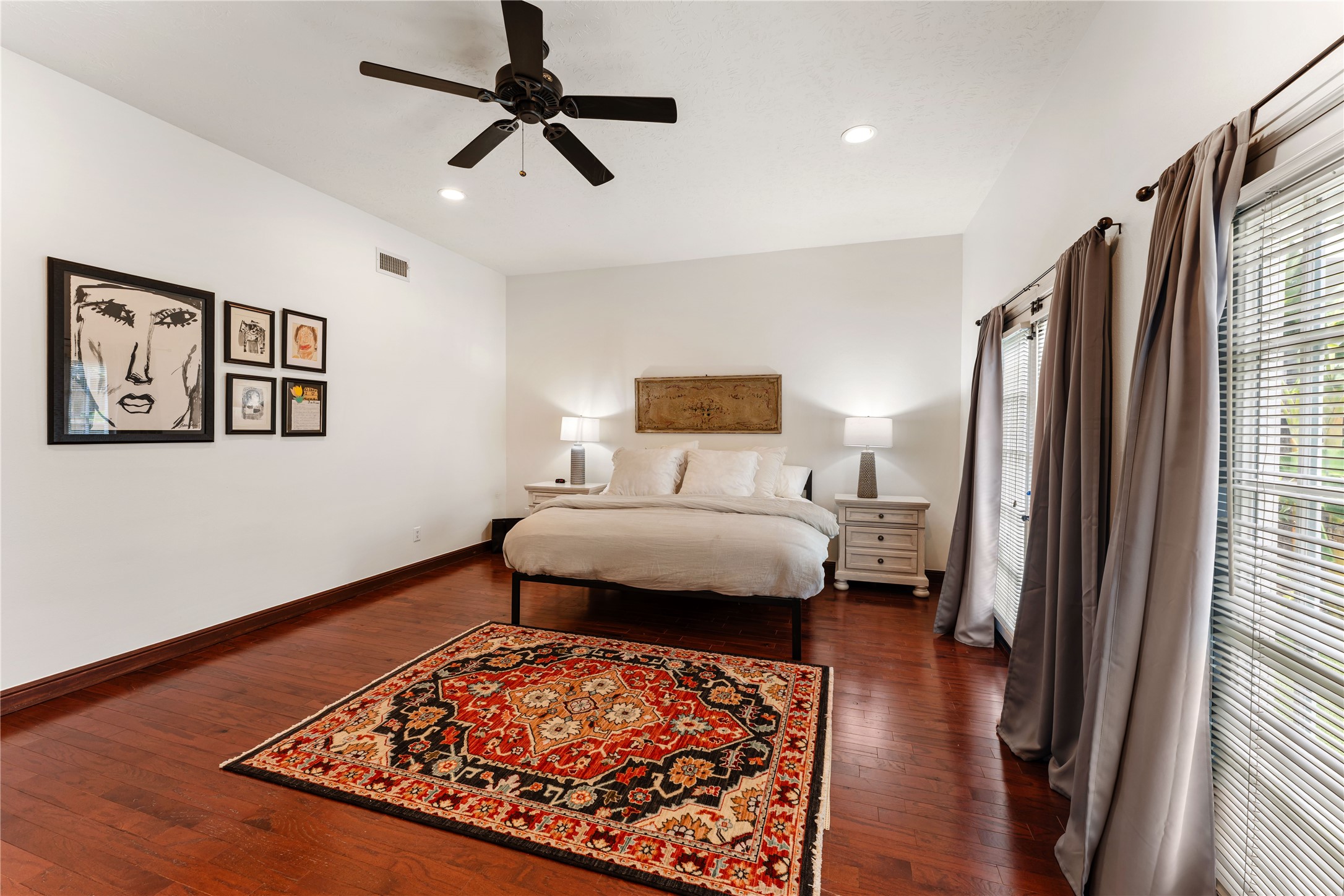 415 West 8th Street Houston, TX 77007 - Photo 8 of 39 The expansive primary suite offers a peaceful sanctuary with generous proportions, abundant natural light, and warm hardwood floors. French doors provide a beautiful connection to the private backyard, creating a tranquil indoor-outdoor atmosphere. Designed for both relaxation and everyday luxury, this retreat feels spacious, bright, and inviting.