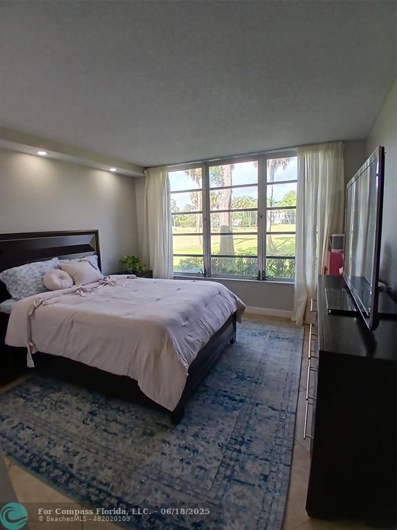 907 Cypress Terrace, Unit 104 Pompano Beach, FL 33069 - Photo 19 of 40 a bedroom with a bed tv and a large window