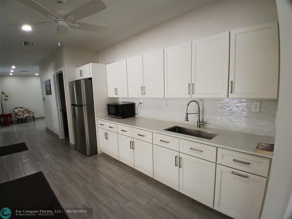 907 Cypress Terrace, Unit 104 Pompano Beach, FL 33069 - Photo 34 of 40 a kitchen with stainless steel appliances granite countertop a refrigerator sink and white cabinets