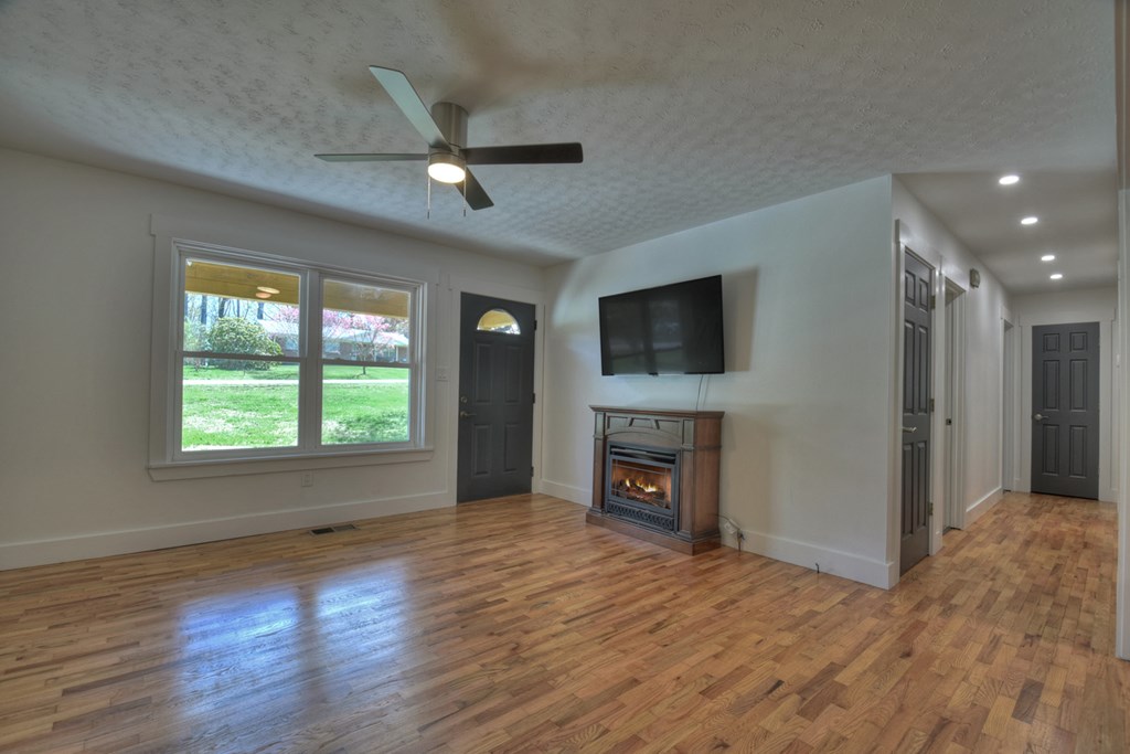 975 Goss Road Epworth, GA 30541 - Photo 14 of 59 an empty room with windows fireplace and a ceiling fan