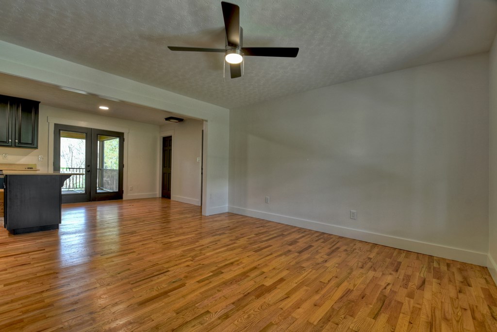 975 Goss Road Epworth, GA 30541 - Photo 17 of 59 an empty room with wooden floor chandelier fan and windows