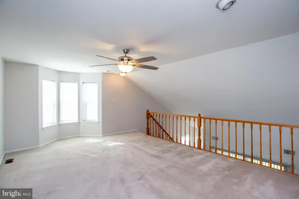 an empty room with a chandelier fan and a window