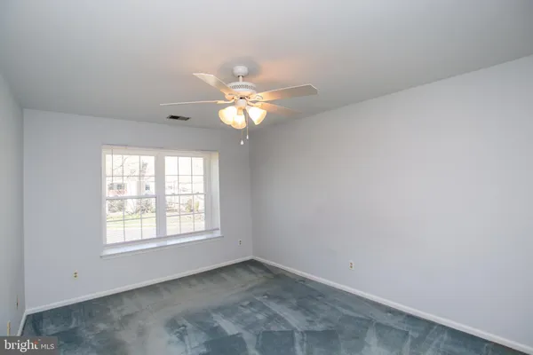 an empty room with windows and chandelier fan