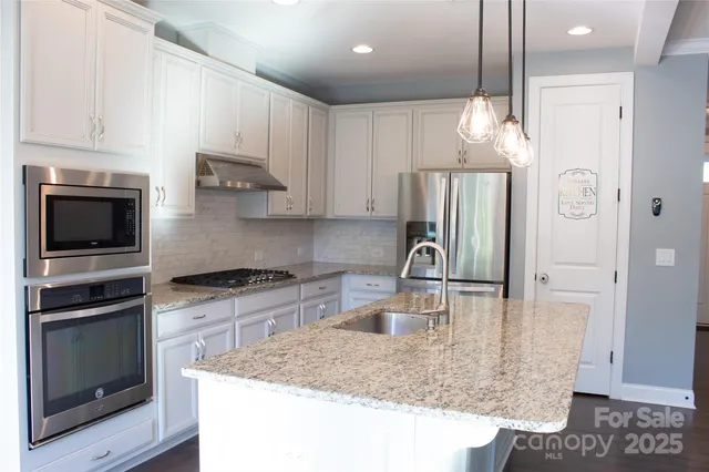 a kitchen with kitchen island granite countertop a sink cabinets and stainless steel appliances