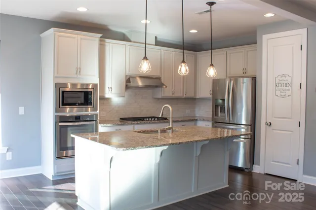 a kitchen with stainless steel appliances granite countertop a refrigerator a sink and a stove