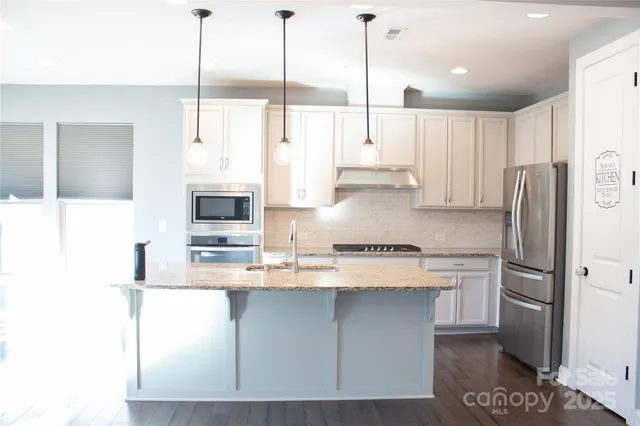 a kitchen with stainless steel appliances granite countertop a refrigerator a sink a stove and a cabinets