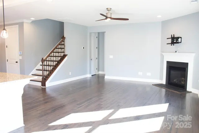 a view of an empty room with wooden floor and a fireplace