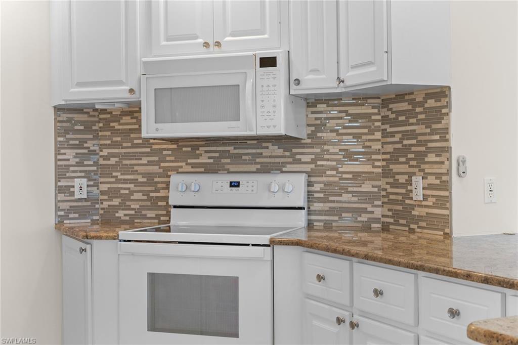 3128 Dominica Way Naples, FL 34119 - Photo 12 of 45 a kitchen with granite countertop white cabinets and white stainless steel appliances
