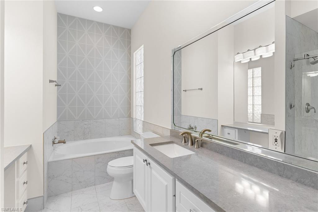 3128 Dominica Way Naples, FL 34119 - Photo 19 of 45 a bathroom with a granite countertop sink a toilet a mirror and a bathtub