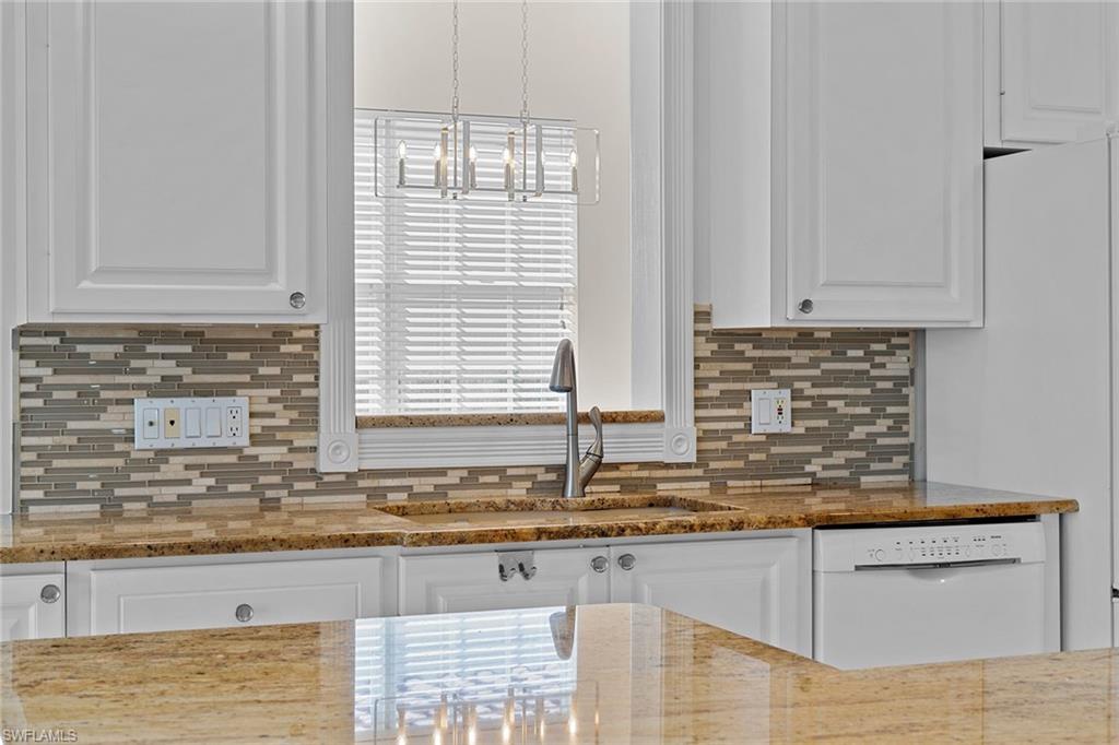 3128 Dominica Way Naples, FL 34119 - Photo 8 of 45 a kitchen with granite countertop a sink a white cabinets and a window