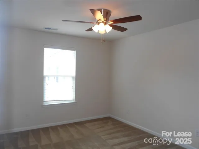 an empty room with a window and a fan