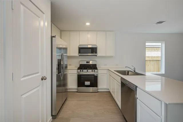 a kitchen with stainless steel appliances granite countertop a stove a sink and a refrigerator