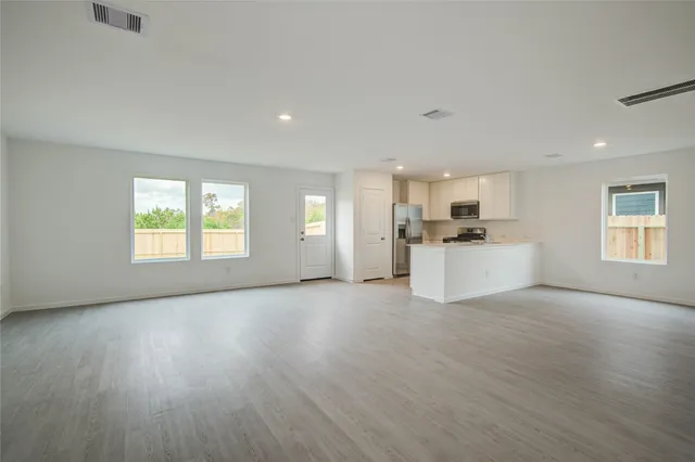a view of a kitchen with a sink stove cabinets and empty room