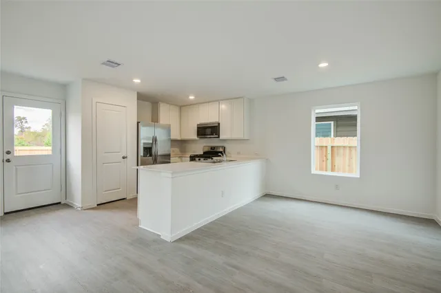 a kitchen with stainless steel appliances granite countertop a refrigerator sink and white cabinets