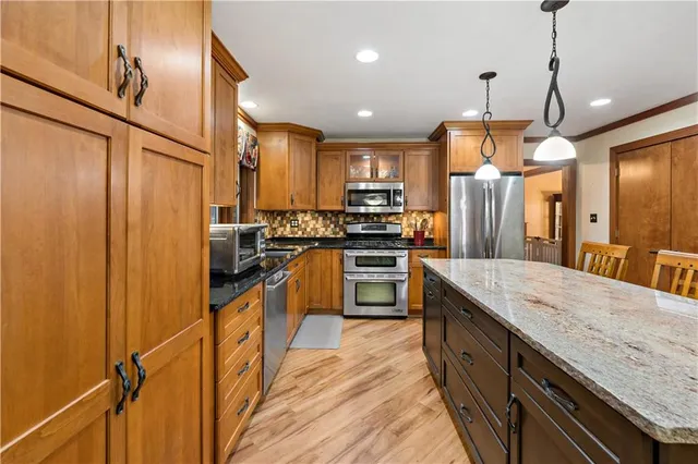 a kitchen with stainless steel appliances granite countertop sink stove refrigerator and cabinets