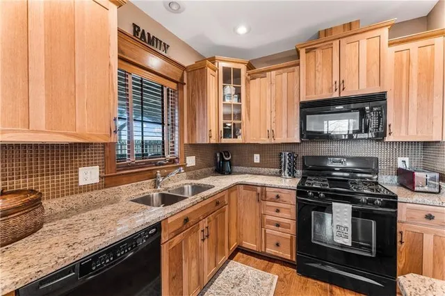 a kitchen with granite countertop a sink a stove and cabinets