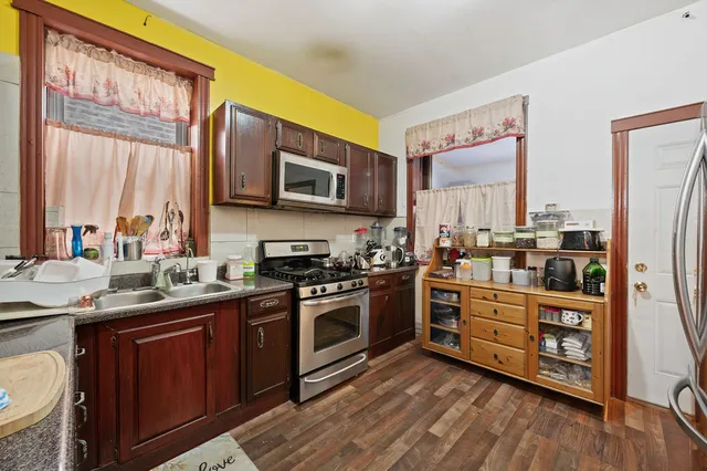 a kitchen with stainless steel appliances granite countertop a stove a sink dishwasher and a microwave oven with wooden floor