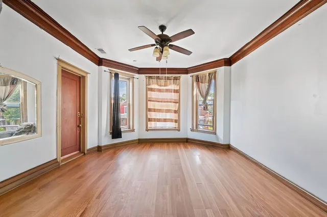 a view of empty room with wooden floor and fan