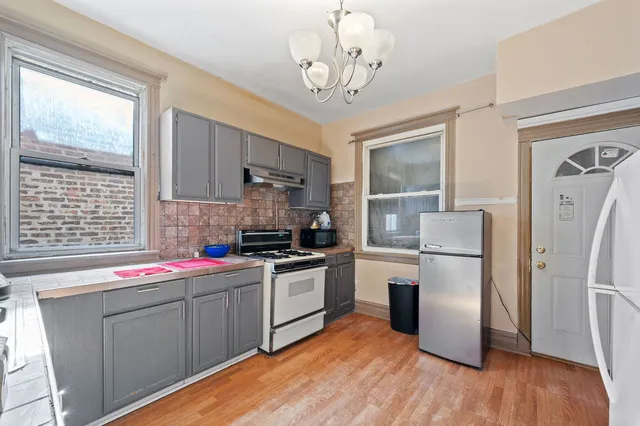 a kitchen with stainless steel appliances granite countertop a sink dishwasher a refrigerator and a stove with wooden floor