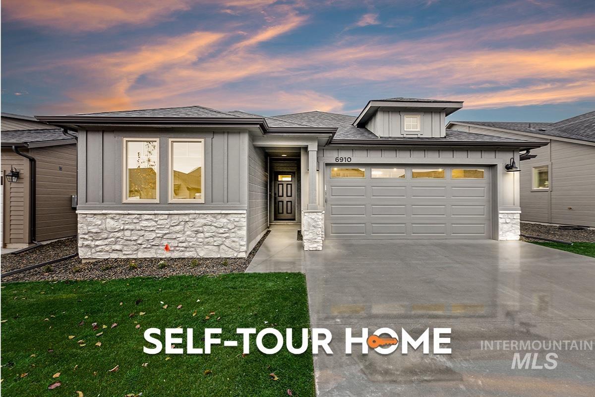 Prairie-style house with stone siding, a shingled roof, concrete driveway, and board and batten siding