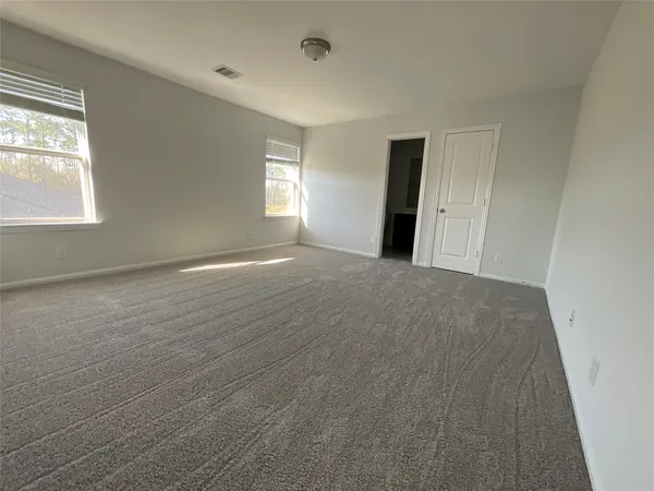 a view of an empty room with window and closet area