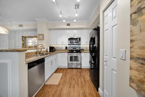 a kitchen with granite countertop a refrigerator and a stove top oven