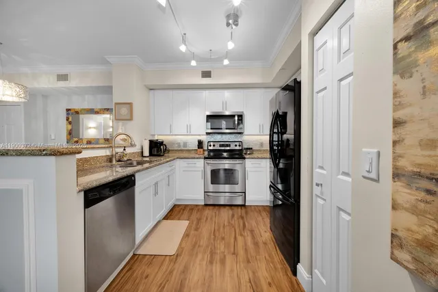 a kitchen with granite countertop a refrigerator and a stove top oven