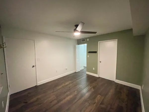 an empty room with wooden floor and a ceiling fan