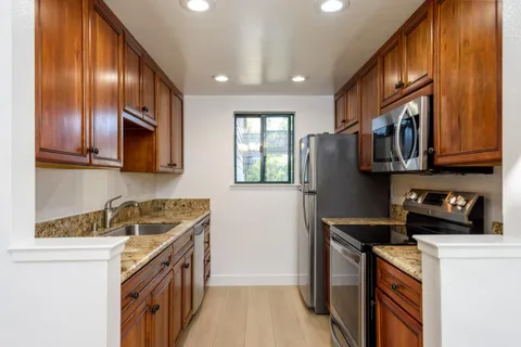 a kitchen with stainless steel appliances granite countertop wooden cabinets a stove top oven a sink and dishwasher