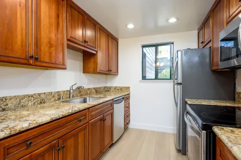 a kitchen with granite countertop cabinets stainless steel appliances a sink and wooden floor