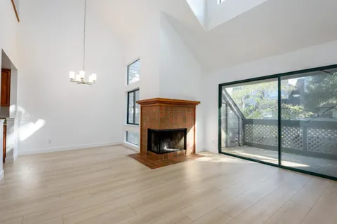 a view of an empty room with wooden floor fireplace and a window