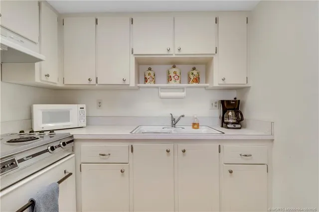 a kitchen with white cabinets and appliances