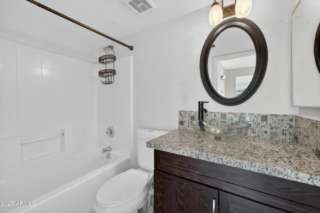 a bathroom with a granite countertop sink mirror and a shower