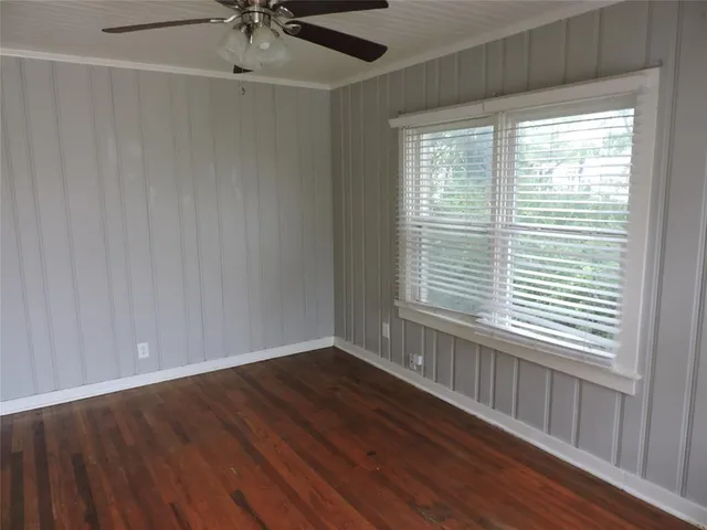 a view of an empty room with a window and wooden floor