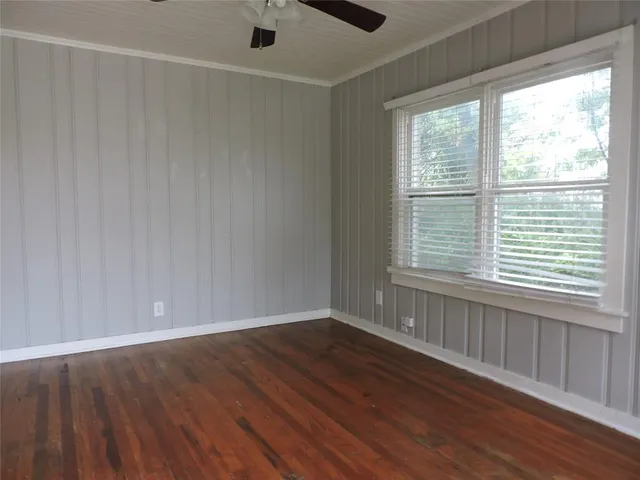 a view of an empty room with wooden floor and a window