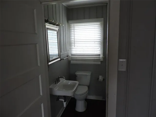 a bathroom with a toilet sink a window and mirror