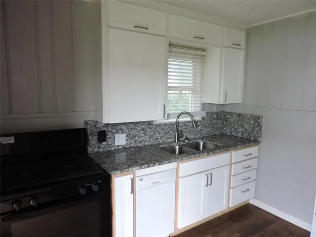 a kitchen with granite countertop a sink and a white cabinets