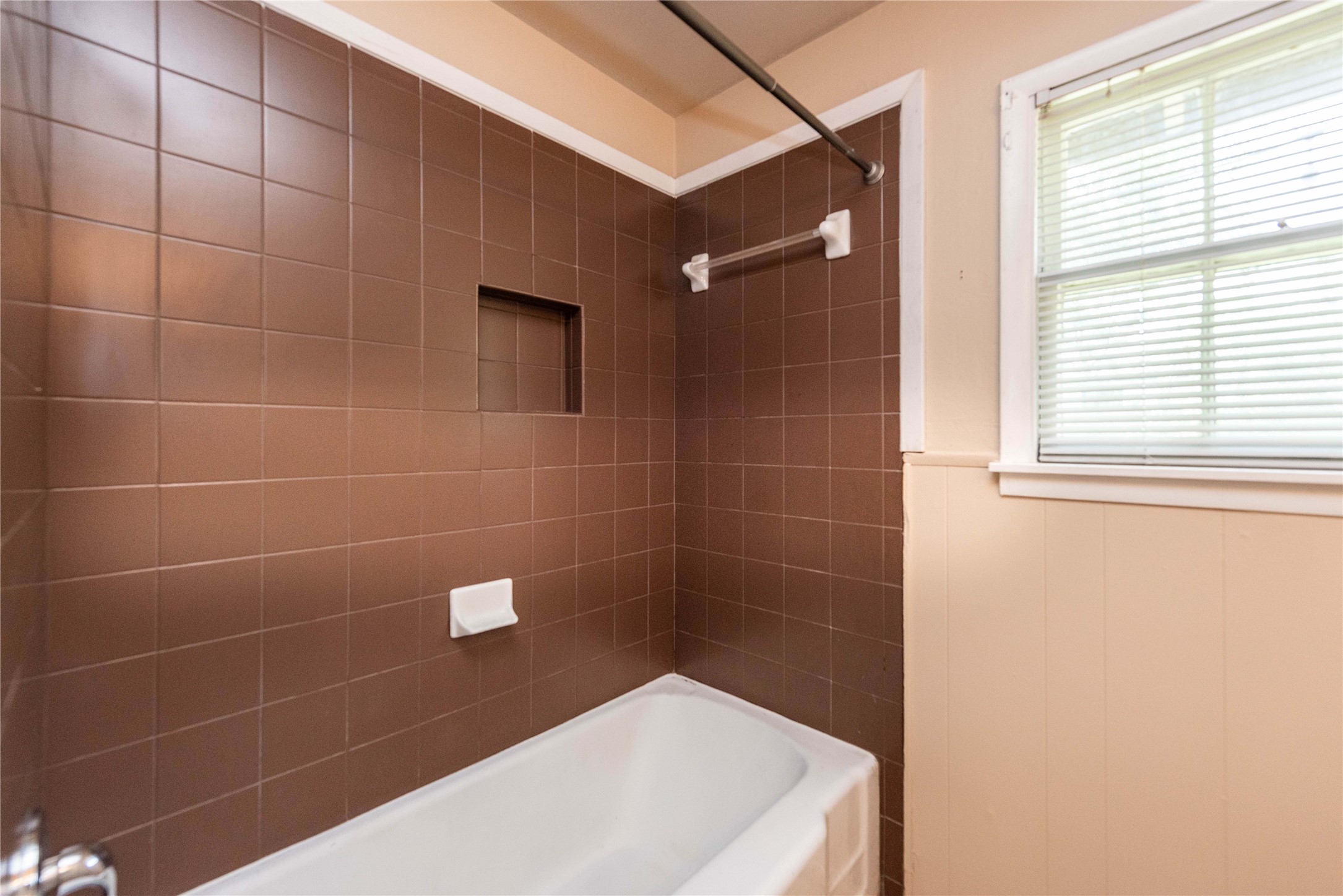 7602 Delafield Lane Austin, TX 78752 - Photo 9 of 17 A window bathes this tiled bathroom in natural light, featuring a convenient shower niche.