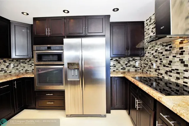 a kitchen with stainless steel appliances kitchen island granite countertop a refrigerator and a stove top oven