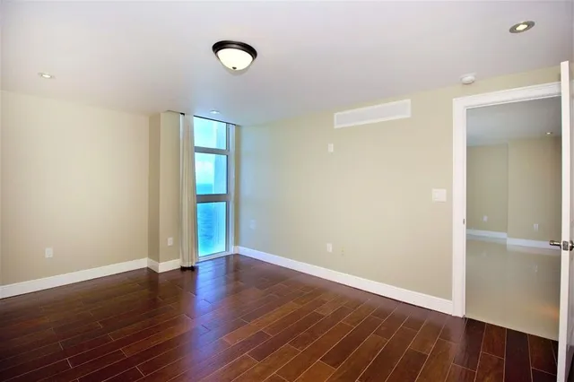a view of a big room with wooden floor and windows
