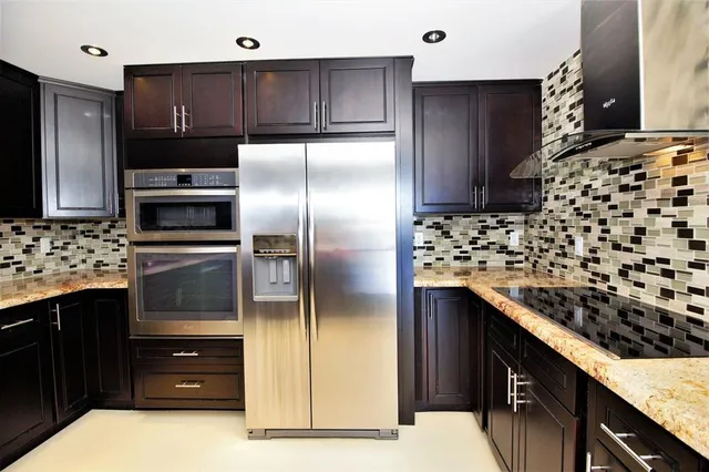 a kitchen with stainless steel appliances granite countertop a stove refrigerator and cabinets